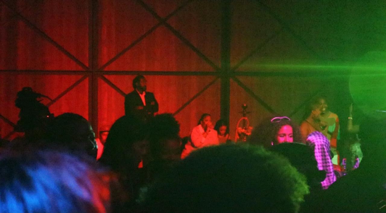 Red and green stage light across a packed live performance room
